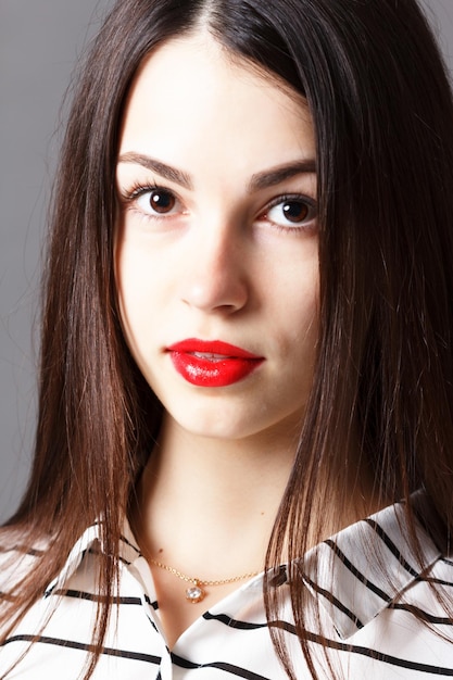 Close up portait of beautiful young woman smiling while applying some facial cream on her cheek