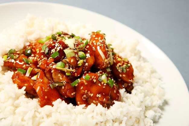 白い皿に盛り付けたご飯とセサミチキンの一部のクローズアップ