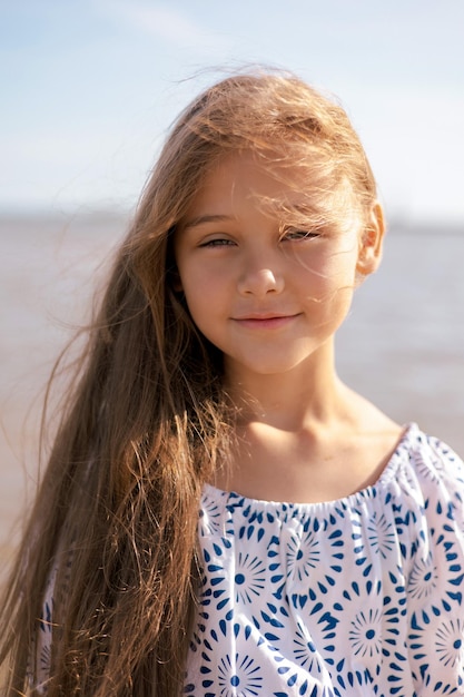 Close up portrait Adorable child girl with long hair outdoors enjoying sunset at beach on summer day