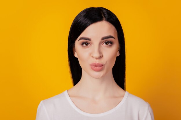 Close up portrait of adorable cute lovely sweet tender girl giving a kiss to you camera isolated yellow background