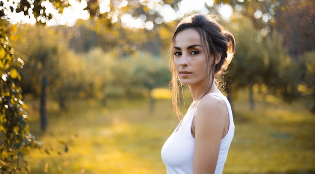 Close up portrait of an adorable and gorgeous brunette woman with profashion make up and hairstyle posing outdoors in sunset with rays of sun Fashion style trendy model