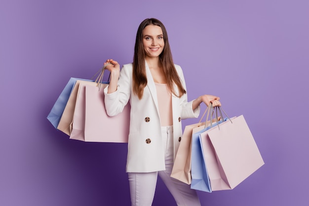 Close up portrait of adorable wealthy lady hold many shop bags posing on violet wall