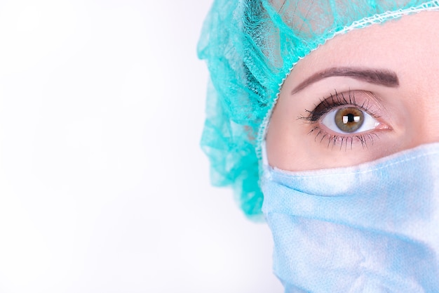 Close up portrait of adult female surgeon doctor wearing protective mask and cap. Half face closeup. Healthcare, medical education, emergency medical service and surgery concept