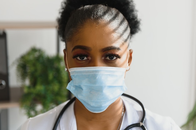 Close up portrait of African American happy female healthcare specialist in medical mask.