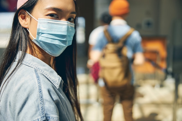 国際空港で写真カメラを見ているアジアの美しい女性の肖像画をクローズアップ