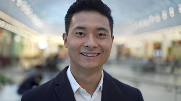 Close up portrait of asian male with braces smiling looking at camera straight