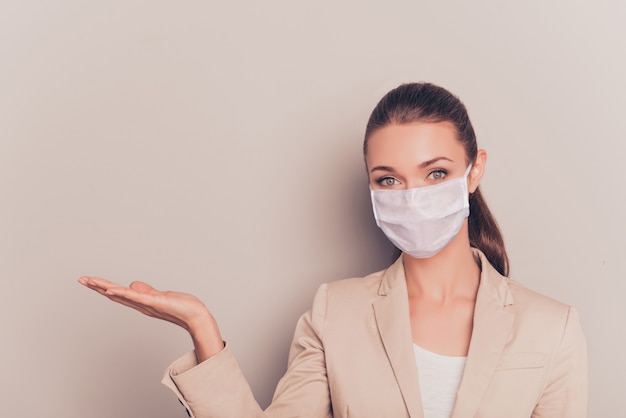 Close-up portrait of  attractive healthy girl wearing white cotton mask holding on palm copy space ncov mers infection safety help disease syndrome therapy isolated on beige color background