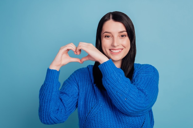 Close-up portrait of attractive lovely girl showing heart gesture valentine day isolated over blue color background