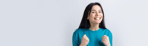 Close up portrait of attractive shouting in winning smiling with raised fists young she her girl wearing jeans shirt clothes isolated on grey background