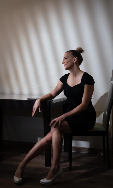 Close up portrait attractive woman in black dress sitting near the table and using phone person