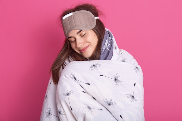 close up portrait of attractive woman with sleeping mask on head and wearing blanket
