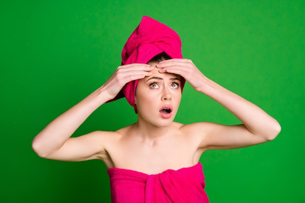 Ritratto ravvicinato di una donna nervosa e preoccupata attraente che indossa un turbante che tocca la fronte isolata su uno sfondo di colore verde brillante