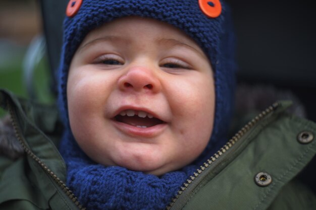 Портрет маленького мальчика в теплой одежде, улыбающегося на открытом воздухе
