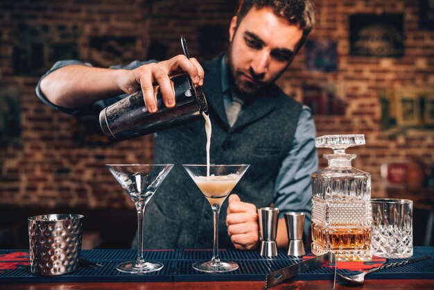 Foto ritratto ravvicinato del barman che versa cocktail fantasiosi nel bar alla festa cocktail di manhattan in