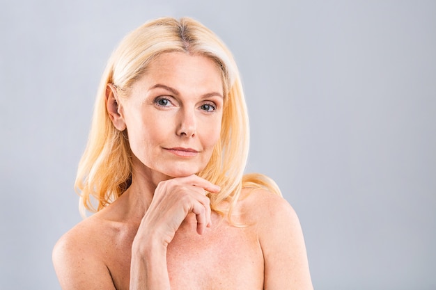 Close up portrait of a beautiful, attractive, charming, naked, nude woman touching her perfect skin, isolated on white background, after shower, peeling, lotion, mask, wellness, moisturizing concept.