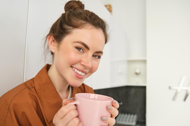 Photo close up portrait of beautiful brunette woman with cup of coffee drinking aromatic beverage from mug