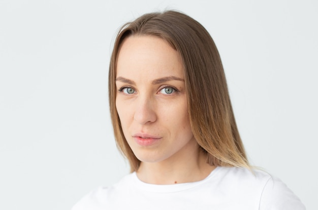 Close-up portrait of a beautiful caucasian young woman looking to the side posing against white wall background. The concept of a beautiful well-groomed woman. Copyspace