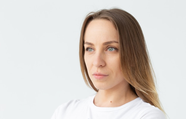 Close-up portrait of a beautiful caucasian young woman looking to the side posing against white wall background. The concept of a beautiful well-groomed woman. Copyspace