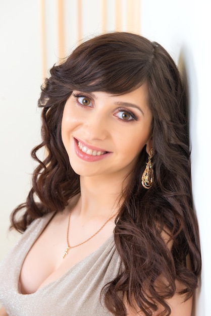 Close-up portrait of a beautiful girl in a gold dress with a neckline.