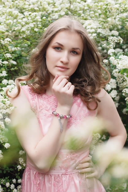 Close up portrait of a beautiful girl in a pink vintage dress standing near colorful flowers. Art work of romantic woman .Pretty tenderness model looking at camera.