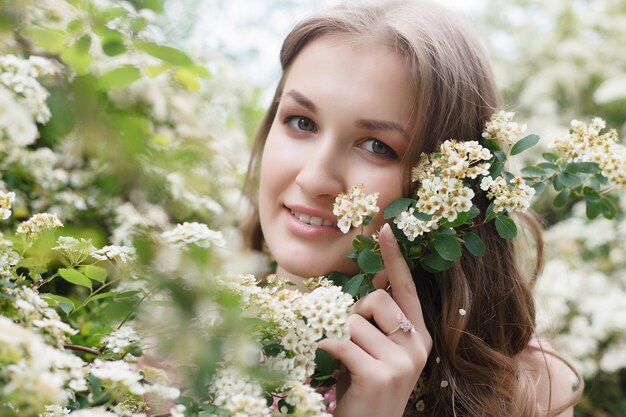 Close up portrait of a beautiful girl in a pink vintage dress standing near white flowers