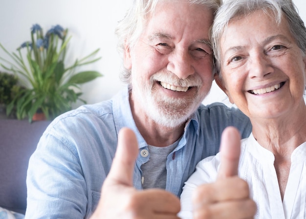 Close up portrait of beautiful happy caucasian senior couple of grandparents looking at camera smiling gesturing ok sign with hands