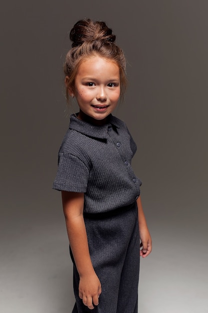 Close-up portrait of a beautiful little girl with dark hair gathered in a bun. Children's fashion portrait.