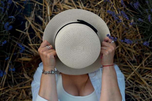 초상화를 닫습니다 아름 다운 사랑스러운 백인 패션 갈색 머리 여자 밀 짚 모자 여름 일몰 자연 야외에서 얼굴을 숨기기