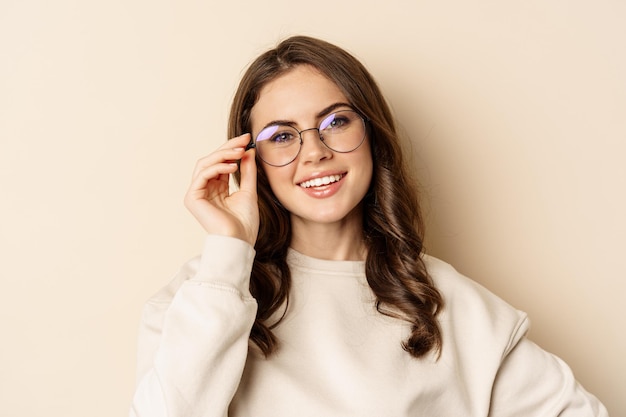 Close up portrait of beautiful modern woman in glasses smiling and looking happy posing in eyewear a...