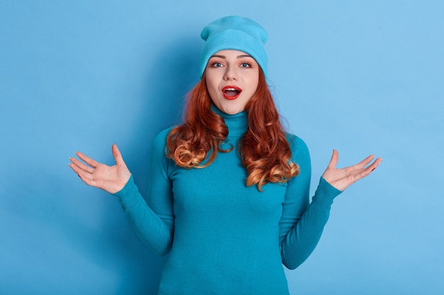 Close up portrait of beautiful red haired woman spreading hands to sides and looking directly 