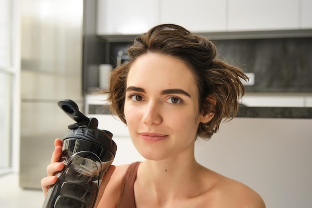 Close up portrait of beautiful sportswoman girl athlete drinks water from sports bottle young fitnes