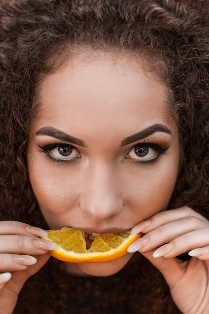 Foto ritratto in primo piano di una bella donna che mangia una fetta di arancia