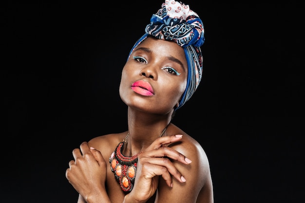 Close-up portrait of a beautiful woman in shawl on head posing isolated on the black wall