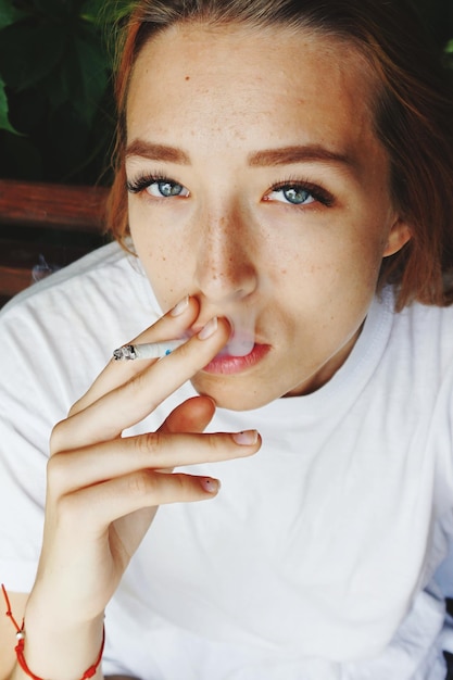 Photo close-up portrait of beautiful woman smoking cigarette