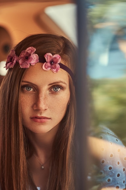 Close-up portrait of a beautiful woman in a white dress and white wreath on the head, sitting in the car in the back seat.