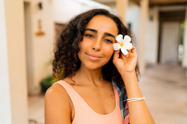 Foto ritratto ravvicinato di bella donna con fiore tropicale in mano in posa in un lussuoso hotel termale concetto di cura del corpo e della stazione termale