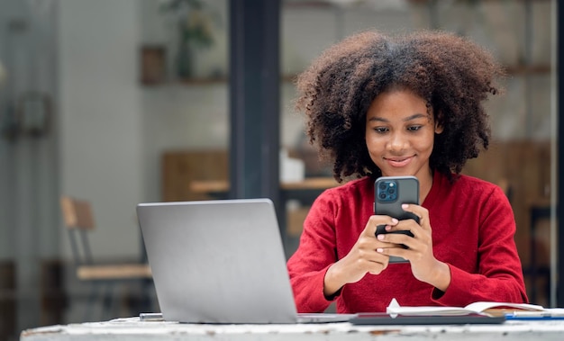 コーヒー ショップで携帯電話でテキスト メッセージを読んで美しい若いアフリカ系アメリカ人女性の肖像画を間近します。