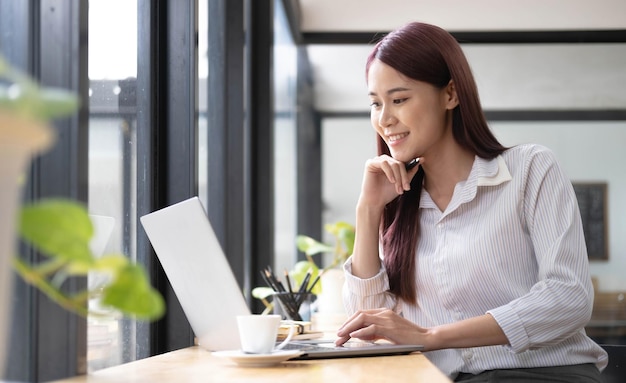 Close up portrait of a beautiful young Asia woman smiling and looking at laptop screen