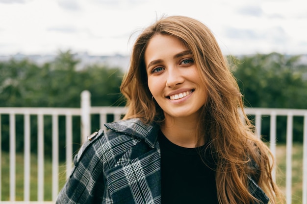 Foto chiuda sul ritratto di bella giovane donna bionda sta sorridendo alla macchina fotografica