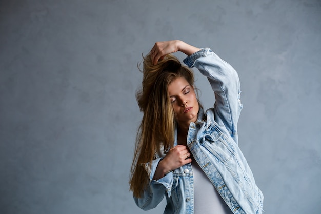 Close up portrait of a beautiful young woman. Emotional sad photo of a girl. Dressed in a white T-shirt and a jeans jacket