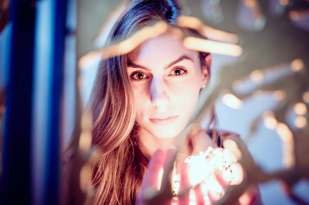 Photo close-up portrait of beautiful young woman holding illuminated lights by railing