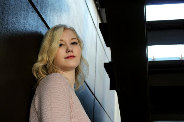 Close-up portrait of beautiful young woman standing against wall