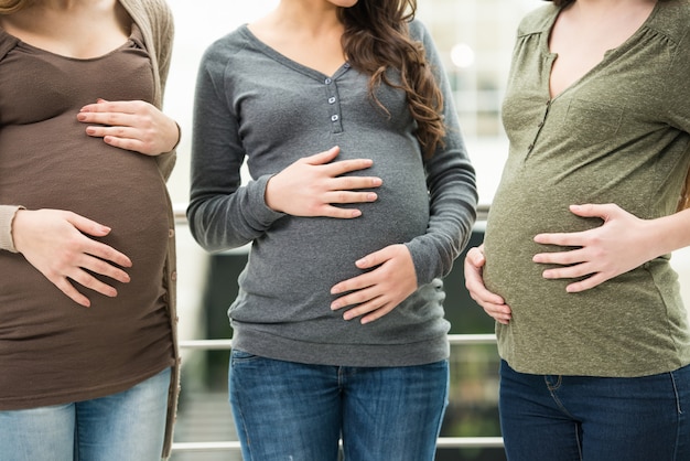 Close-up portrait of bellies of three pregnant women.