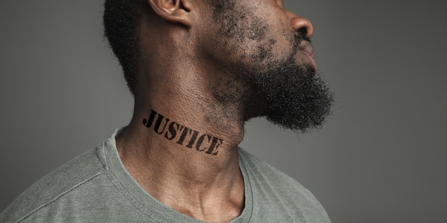 Close up portrait black man tired of racial discrimination has\
tattooed slogan justice on his neck. concept of human rights,\
equality, justice, problem of violence and racism, discrimination.\
flyer.