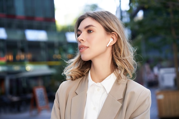 Close up portrait of blond businesswoman confident corporate woman in headphones and beige suit posi