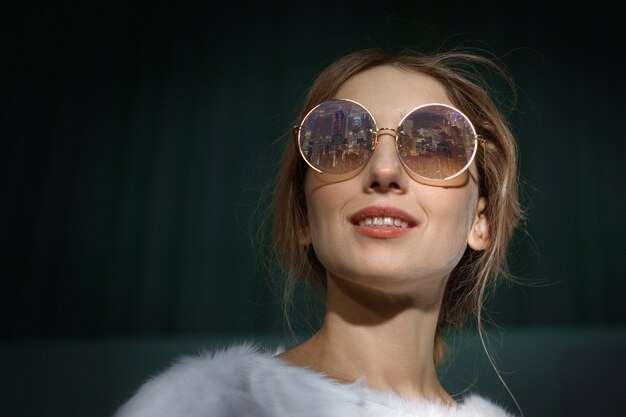 Close up portrait of blonde girl in sunglasses with reflection of city