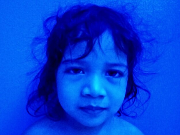 Close-up portrait of a boy against blue background
