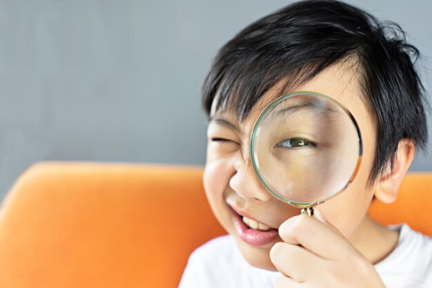 Close-up portrait of boy looking through magnifying glass