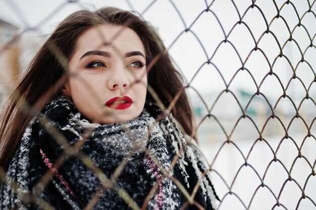 Close up portrait of brunette girl in scarf against cage.