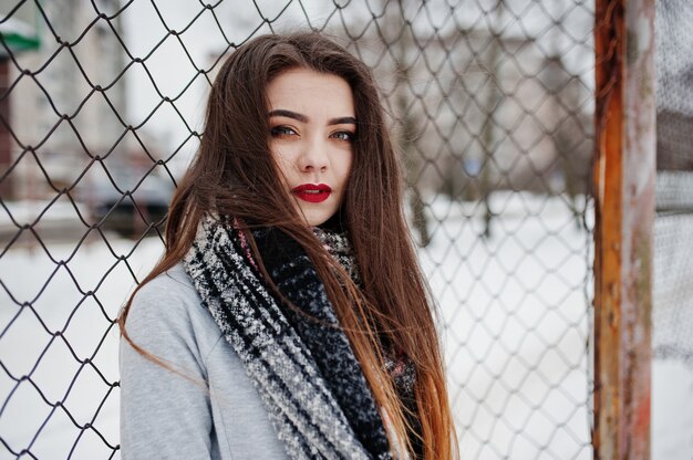 Close up portrait of brunette girl in scarf against cage.